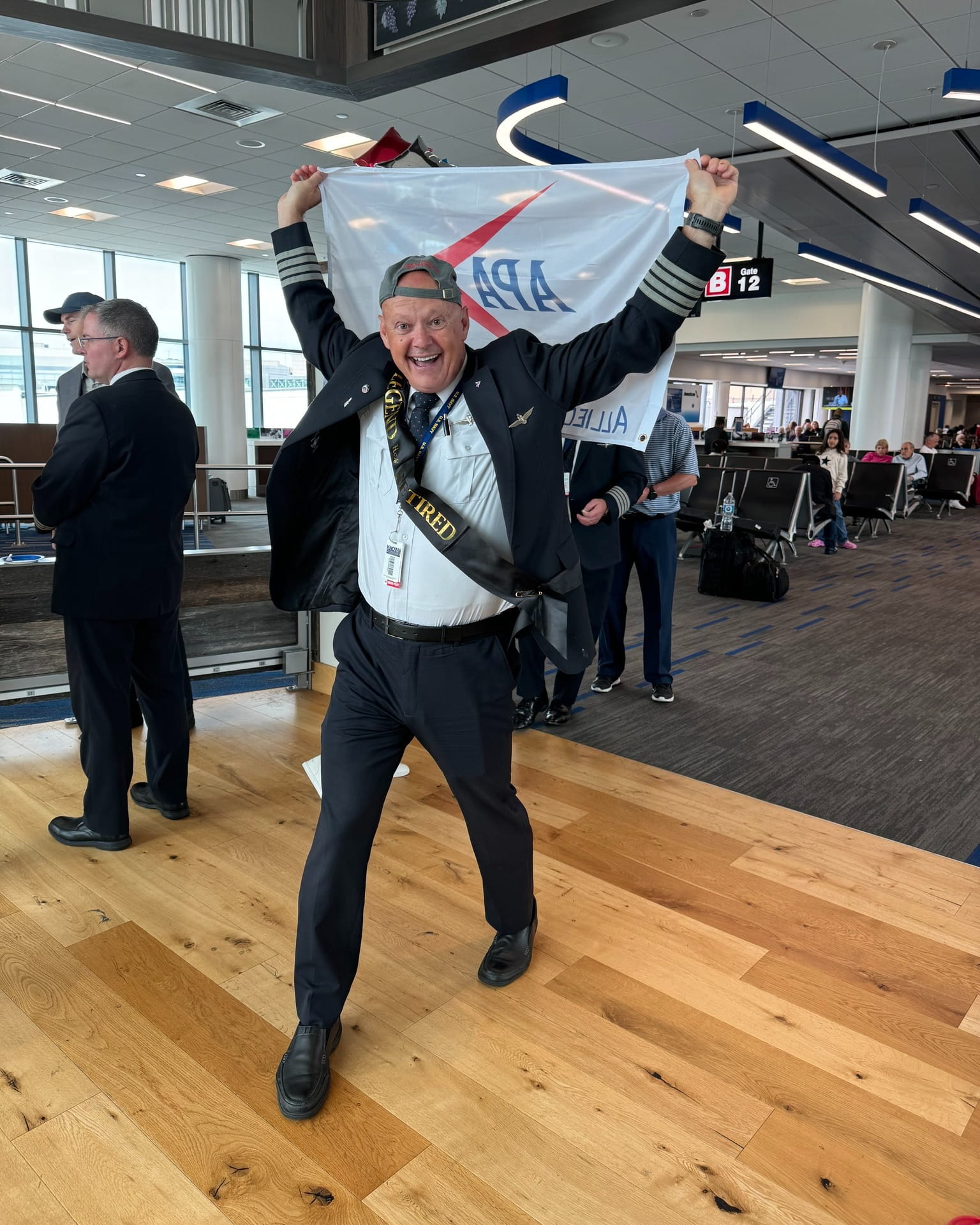 a pilot carrying an APA flag and wearing a retiree sash