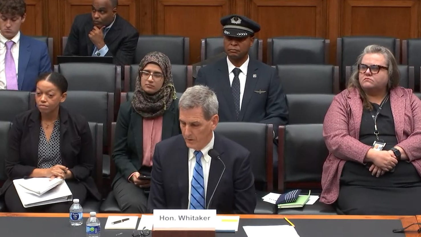 a man in a suit testifying before a Congressional committee