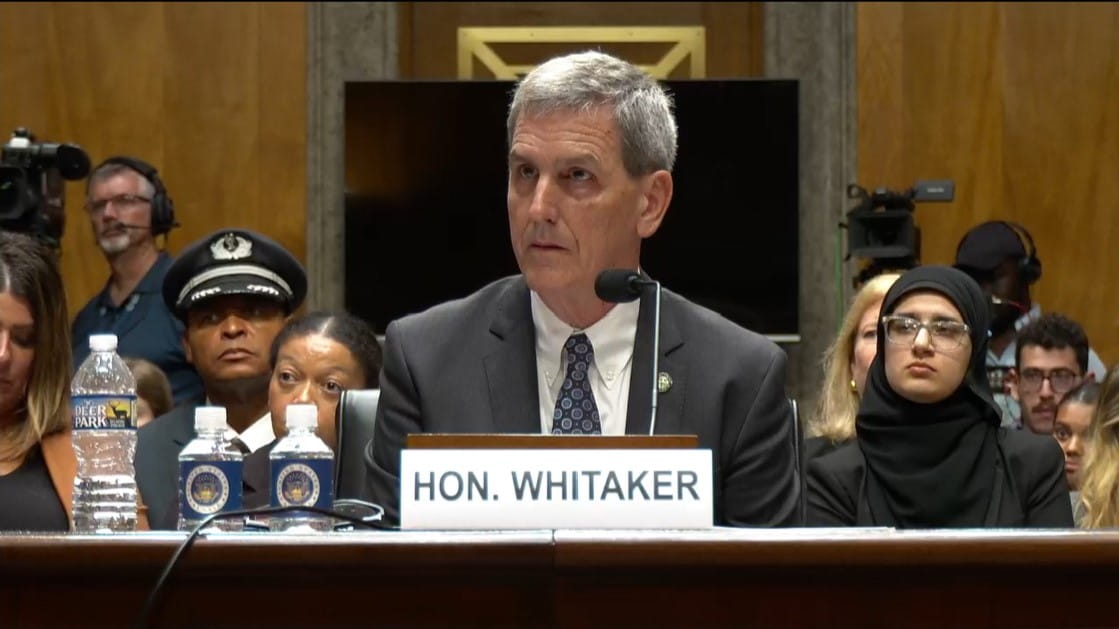 a man in a suit testifying before a Congressional committee