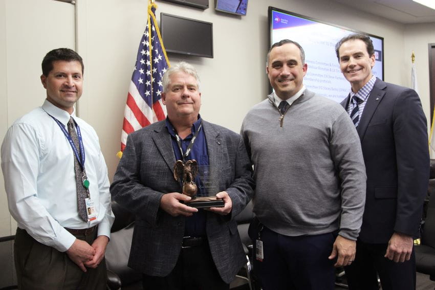 four pilots, one of whom is holding a trophy