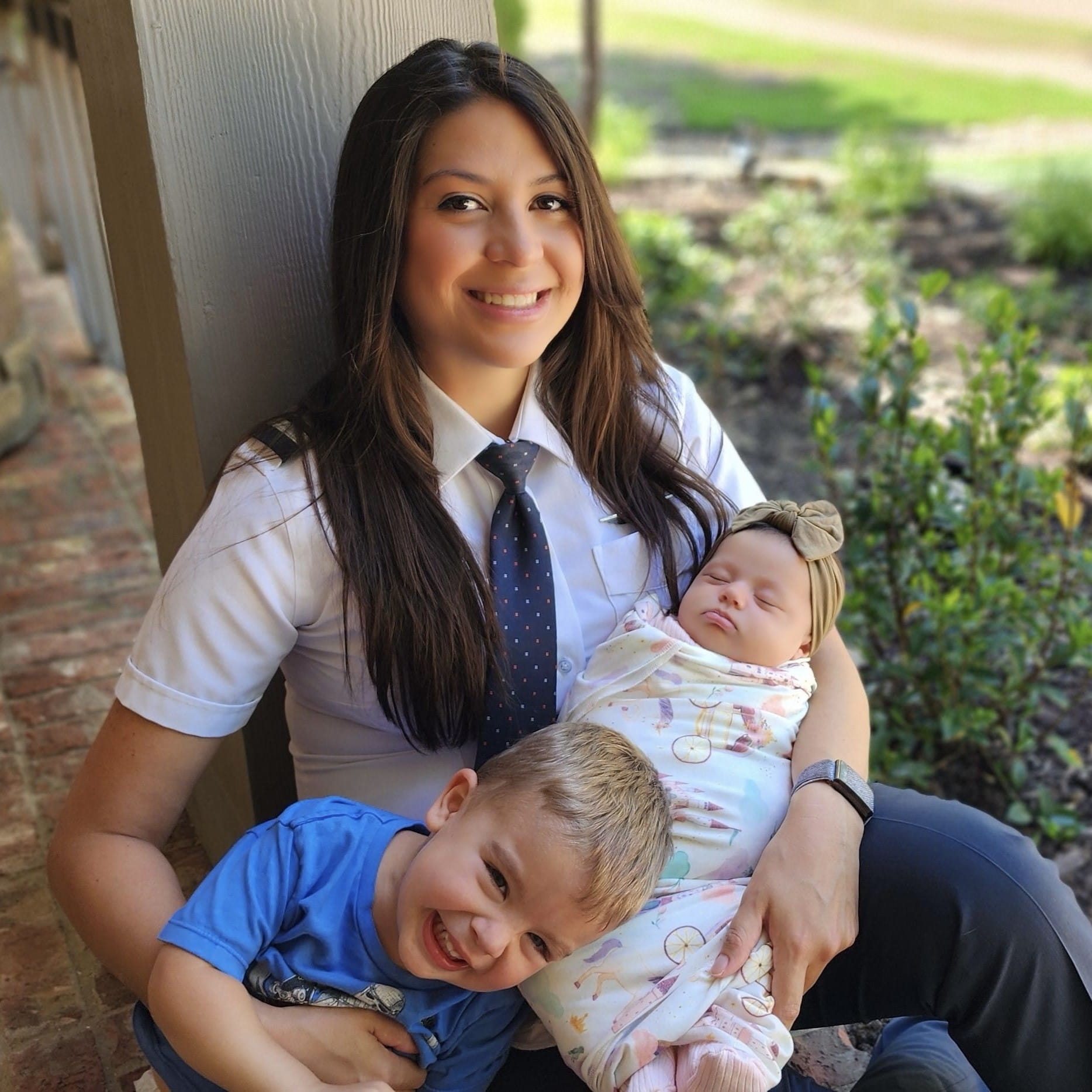 a female pilot holding a toddler and a baby