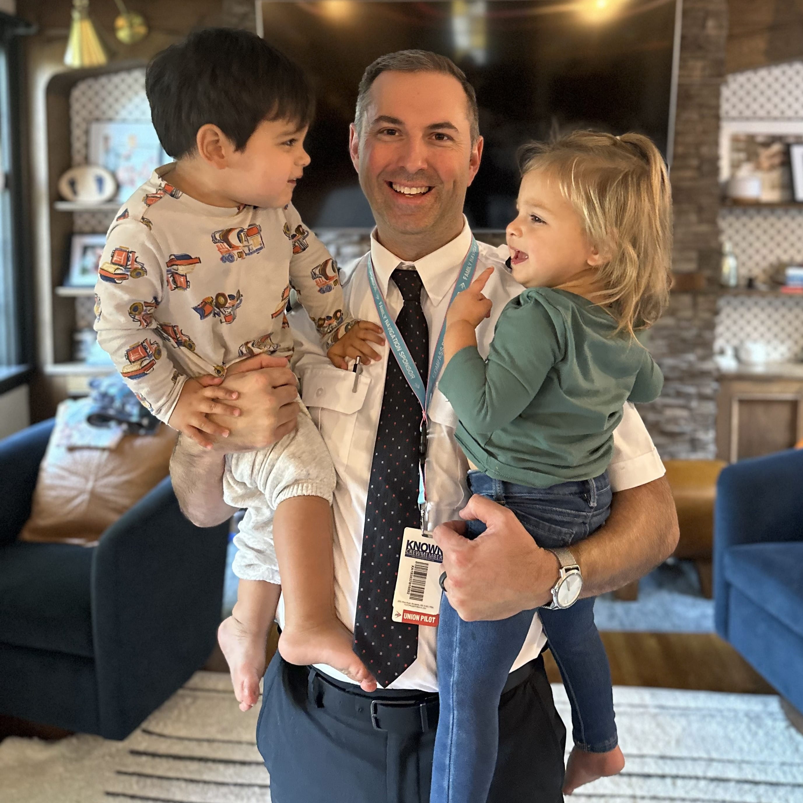 a male pilot holding two toddlers