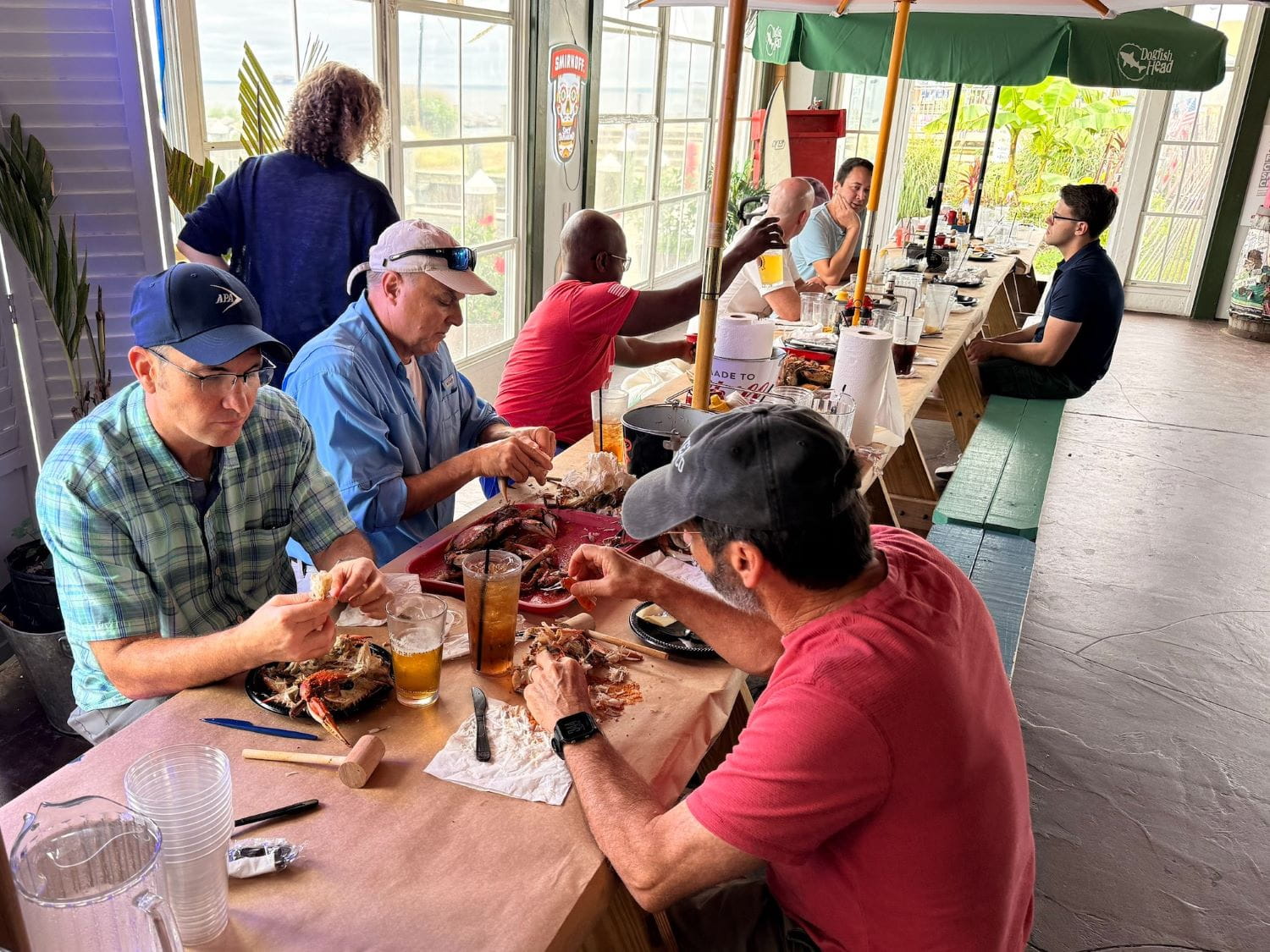 a group of men in baseball caps eating crab at a picnic table